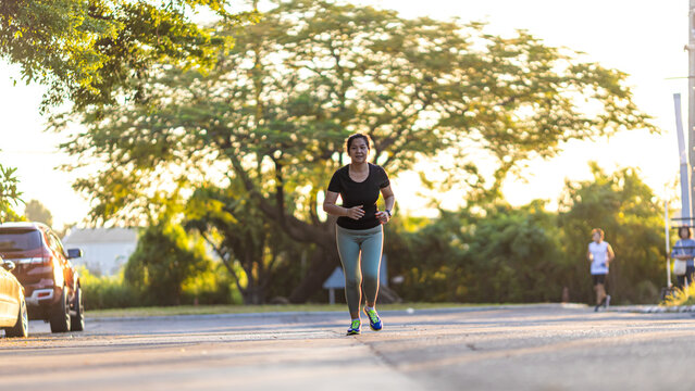 Woman morning run on city road sun light healthy community
