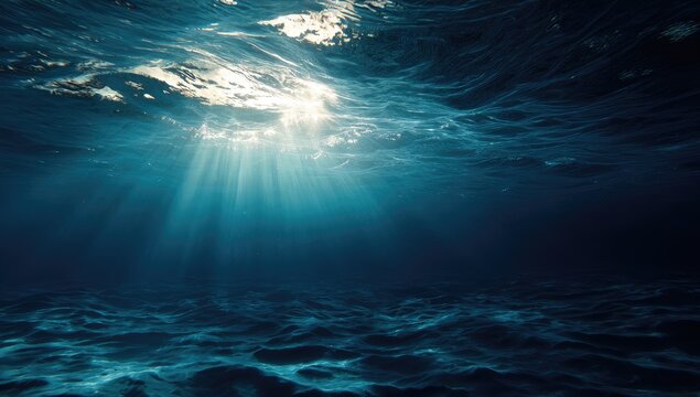Sunbeams penetrate deep ocean water, illuminating a dark, textured seabed;  light rays diffuse, creating a dramatic underwater scene