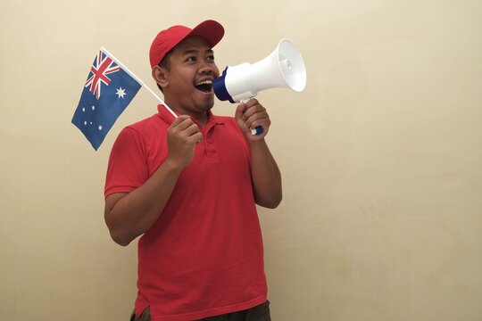Southeast Asian man holding Australian flag and megaphone, promoting visa, scholarship, or study abroad opportunities in Italy; isolated with copy space for advertisement.