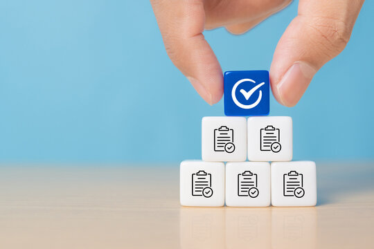 Hand holding white correct sign mark on blue dice and the top of document icon for ISO quality control certification and project approval concept.