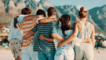 People, friends and back view with hug on beach for summer vacation, bonding or outdoor fun. Group, community or embrace with sunshine on ocean coast for travel, holiday or weekend together in nature