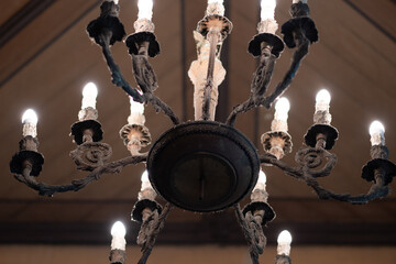 Close up ornate chandelier glows warmly multiple candle-shaped bulbs timeless elegant ambiance overhead