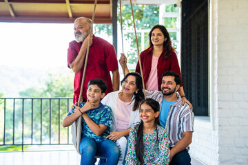 Indian family enjoying laughter and bonding moments on swing in home porch outdoors