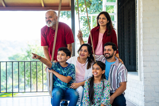 Indian family enjoying laughter and bonding moments on swing in home porch outdoors