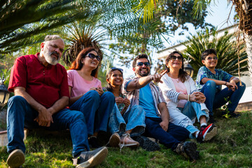 Indian family sitting on lawn slope outdoors enjoying chitchat and quality bonding time together