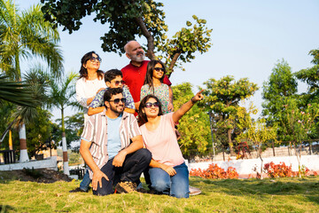 Indian family on lawn pointing ahead together, smiling and promoting an outdoor advertising idea