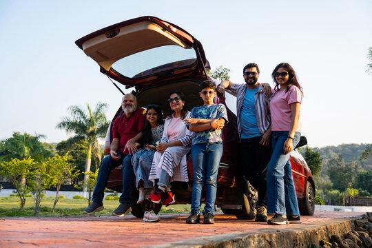 Indian family sitting in car dicky outdoors, enjoying laughter and bonding before a picnic