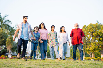 Indian family walking through green farm fields enjoying nature and joyful family togetherness