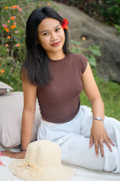 Relaxed young woman enjoying a colorful outdoor picnic in nature with fruits and flowers.