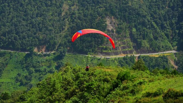 Colorful paragliding athletes on golden rice terraces in Khau Pha pass, Mu Cang Chai town near Sapa city, North of Vietnam. Beautiful terraced rice field in harvest season in Yen Bai province.