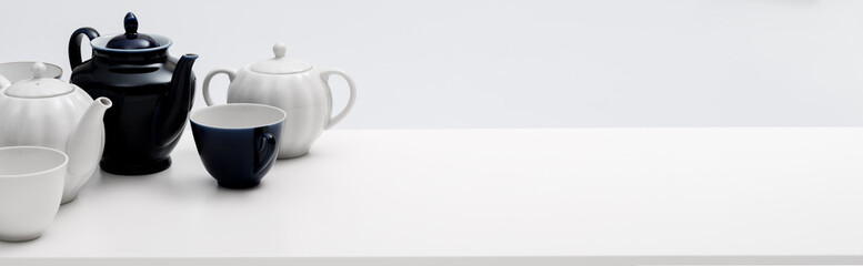 Ceramic teaware. Teapot, cup, and saucer on a white table. Light background. Banner.