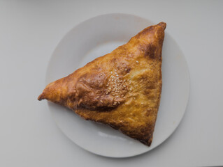 A meat and sesame pie on a white plate. View from above.