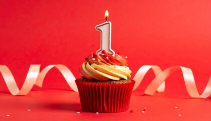 Cupcake with white frosting and lit number one candle in red liner on red background.