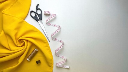 Yellow fabric and necessary sewing tools for creating clothes and repairing items.