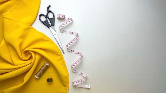 Yellow fabric and necessary sewing tools for creating clothes and repairing items.