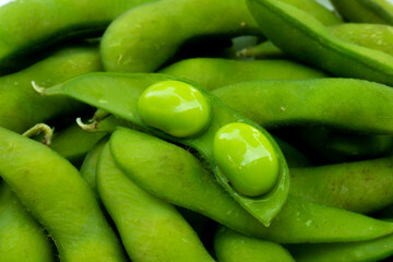 Close up of green edamame pods and beans on white plate