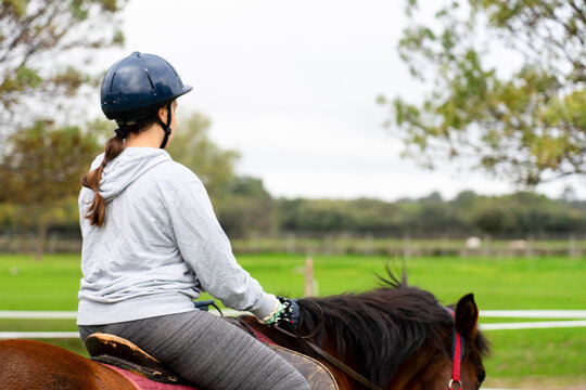 Young girl horseback riding enjoying equestrian sport outdoors