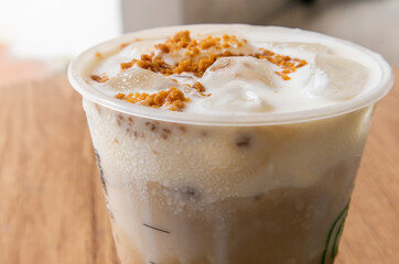 Iced coffee latte with creamy cold foam and caramel crumble. top view of Salted caramel milkshake with coffee on wooden table