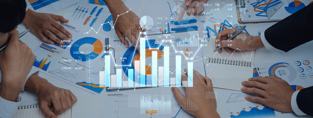 A team actively collaborates on business strategy, utilizing data analysis, graphs, and financial documents, enhanced by a digital overlay in a modern office setting. Scalp
