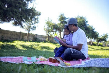 Obraz premium Tender Moment as Father and Daughter Read Book Together During Picnic