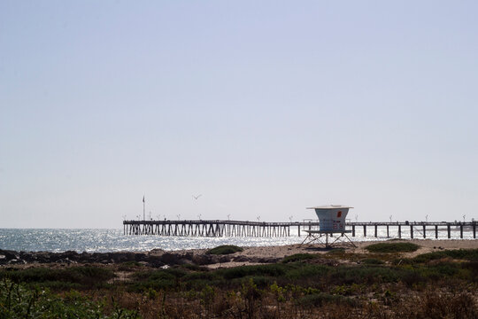 Lifeguard tower and ocean pier under bright midday sun