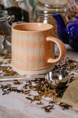 Mug of hot tea with measuring spoon, teapot, and storage jars