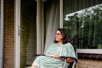 Coach relaxes on patio chair smiling with journal in hand