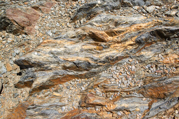 brown shiny rock, crystalline slate in the mountains