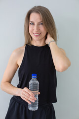 Smiling Woman Holding a Water Bottle, Emphasizing Hydration and Wellness
