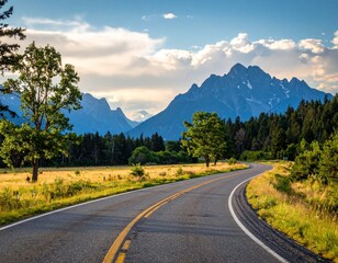 Fototapeta premium Winding Road Leading to Mountain Range Under Partly Cloudy Sky