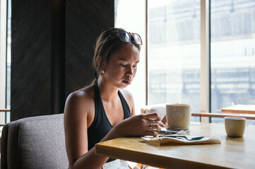 Young asian woman using a smartphone in a coffee shop, Bangkok, Thailand