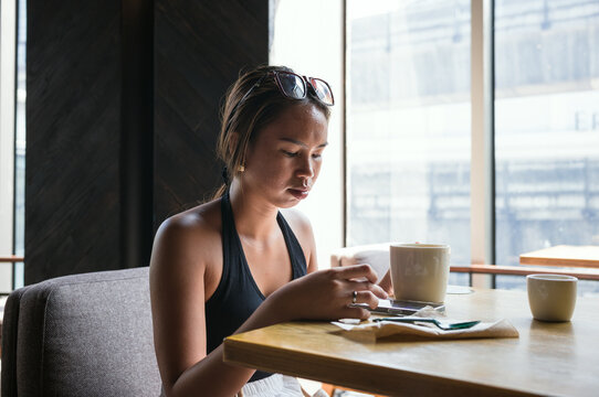 Young asian woman using a smartphone in a coffee shop, Bangkok, Thailand