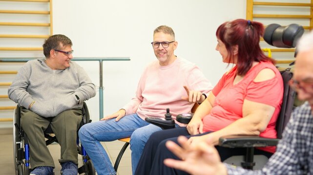 Diverse people in wheelchairs talking in an inclusive community group