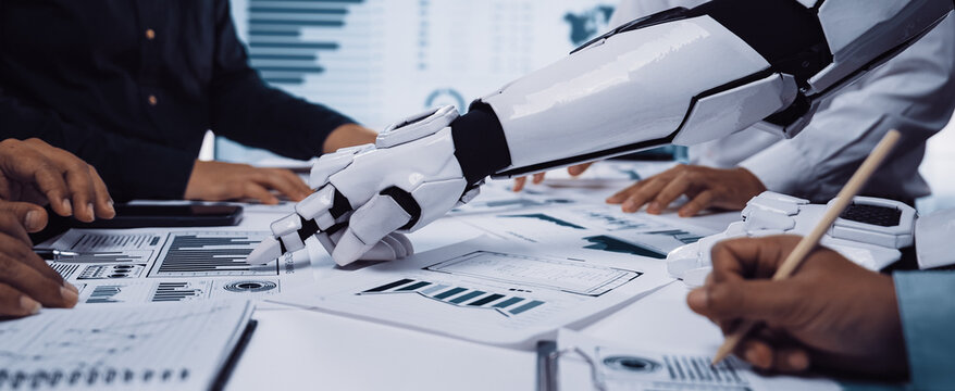 A robotic arm assists a business team in analyzing data and creating presentations in a modern office, showcasing the integration of technology and teamwork.Noogenesis