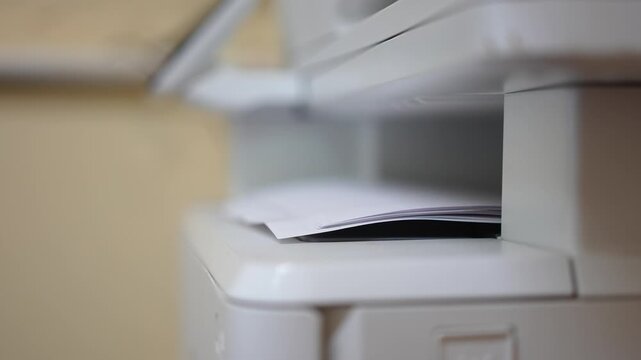 Many of A4 white paper were printing out from photocopy machine in fast motion, Close-up with selective focus.