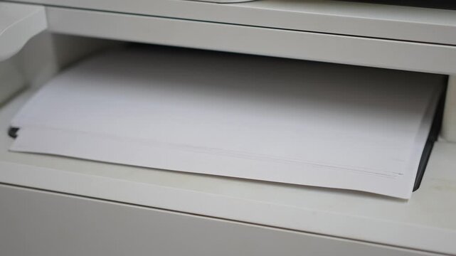 Many of A4 white paper were printing out from photocopy machine in fast motion, Close-up with selective focus.