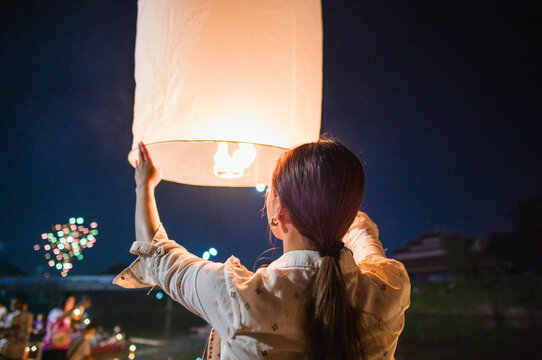 Asian woman releasing a paper lantern during Yi Peng festival, Chiang Mai, Thailand