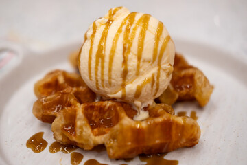 Vanilla ice-cream on the croffle, a hybrid of a croissant and waffle, served on plate with caramel sauce
