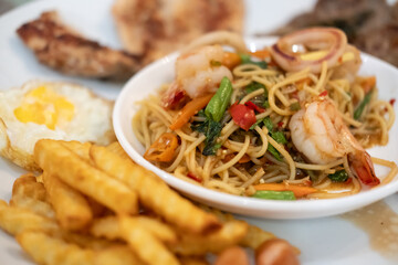 Spicy seafood spaghetti served on white plate, with french fries