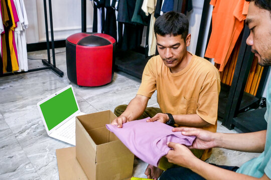Two Men Meticulously Folding and Packing New Apparel Inventory in Stylish Boutique