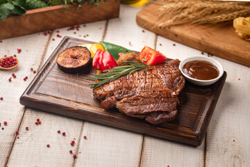 Juicy grilled steak served with roasted vegetables and herbs on wooden board