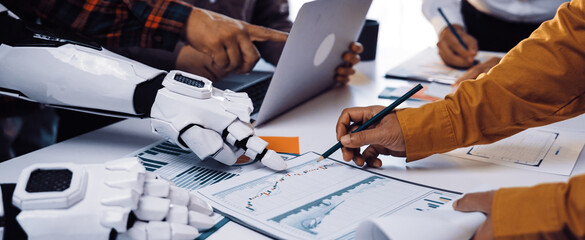 A diverse team collaborates in a modern workspace, utilizing a robotic arm alongside humans to analyze data and discuss progress on various projects.Noogenesis