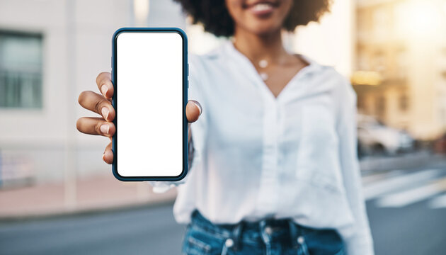 Woman holding up a blank smartphone screen in an urban setting with a blurred background outdoors - Powered by Adobe