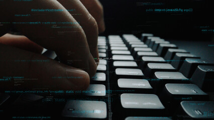 A close-up view of hands typing on a keyboard, surrounded by a code overlay, symbolizing...