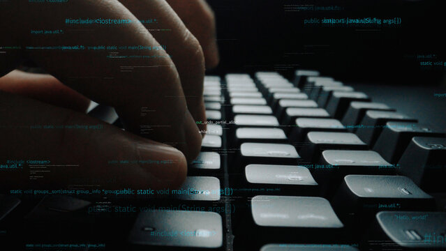 A close-up view of hands typing on a keyboard, surrounded by a code overlay, symbolizing programming and digital technology in a modern workspace. Xenic