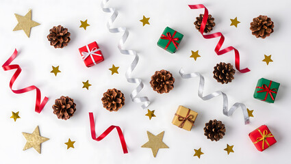 Minimal flat lay of Christmas decorations on white background &mdash; pinecones, stars, ribbons, small gifts.