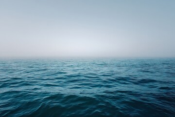 Obraz premium Ocean Surface with Blue Water and Foggy Horizon under a Cloudy Sky