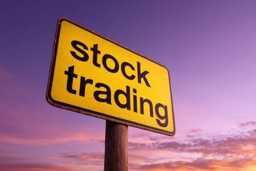 A yellow stock trading sign against a dusk sky with shades of purple and orange