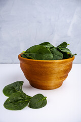 fresh spinach leaves in a wooden bowl on a white background