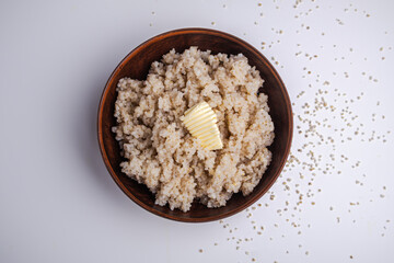 Barley porridge with butter in a clay bowl on a white background